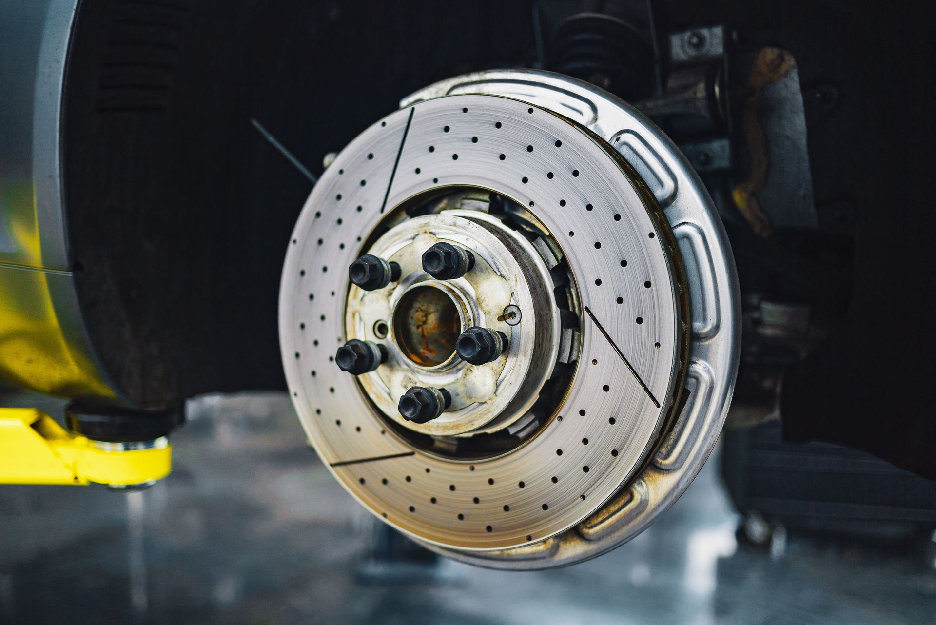 Metal disk brake fixed on car without wheel during repair service in workshop