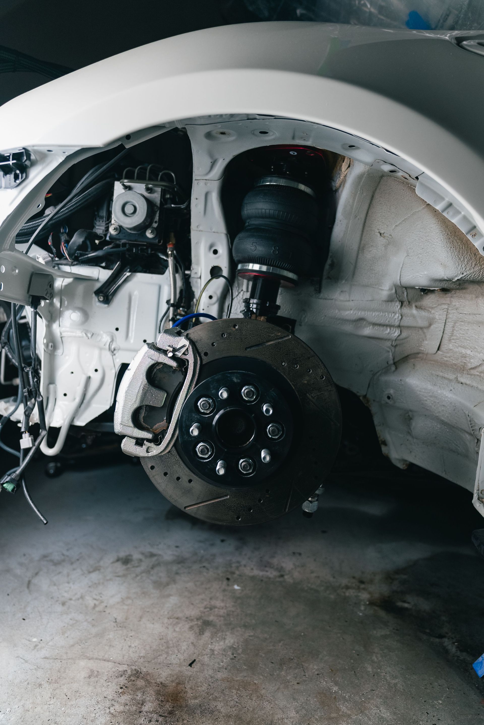 Close-up shot of a vehicle's suspension and brake assembly in a garage setting.